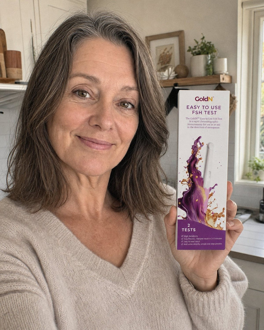 Woman in her fifties in a kitchen holding the GoldN FSH Test box