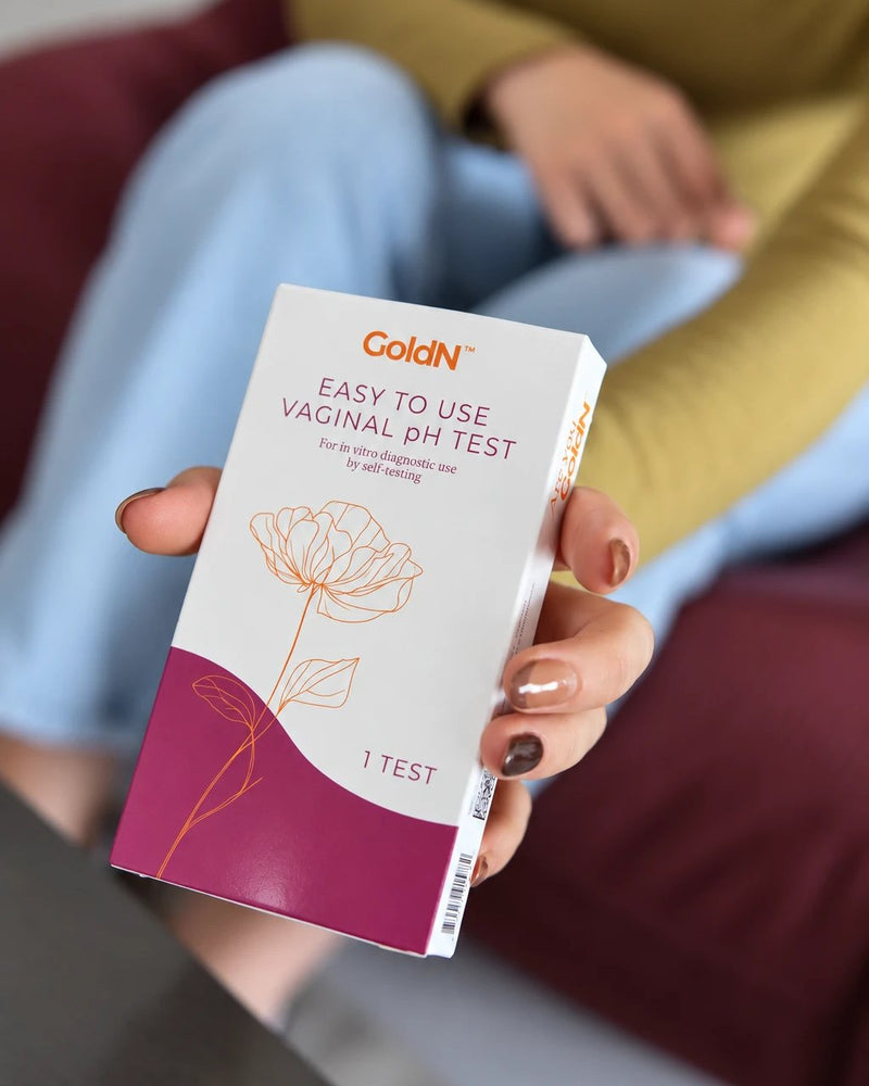 Hand holding the GoldN Easy To Use Vaginal pH Test box toward the camera, front label in focus