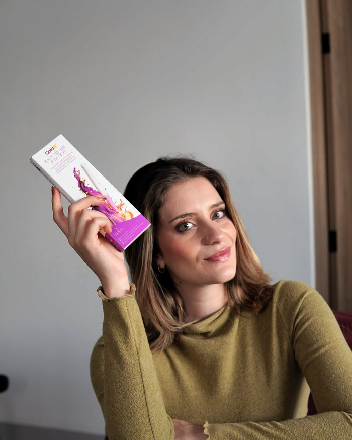 Woman on a sofa holding the GoldN FSH test box