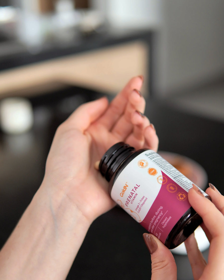 Hands opening the GoldN Prenatal with CoQ10 bottle with capsules in the palm