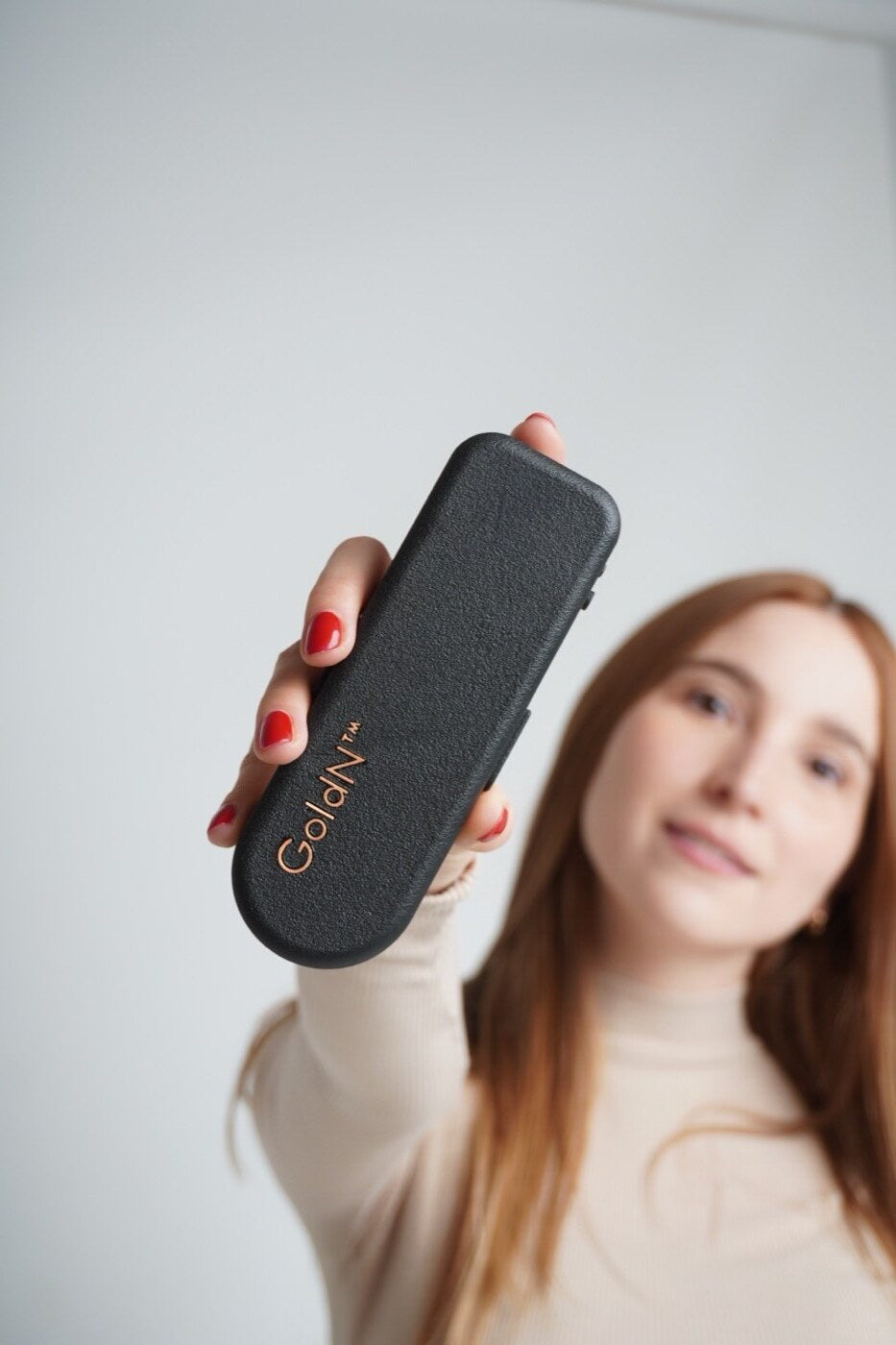 Hand holding a GoldN case with soft studio light