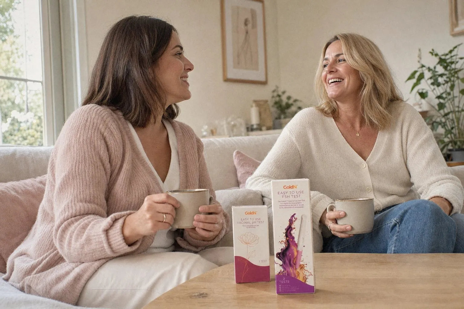 Two women talking on a sofa, GoldN pH and FSH test boxes on the coffee table